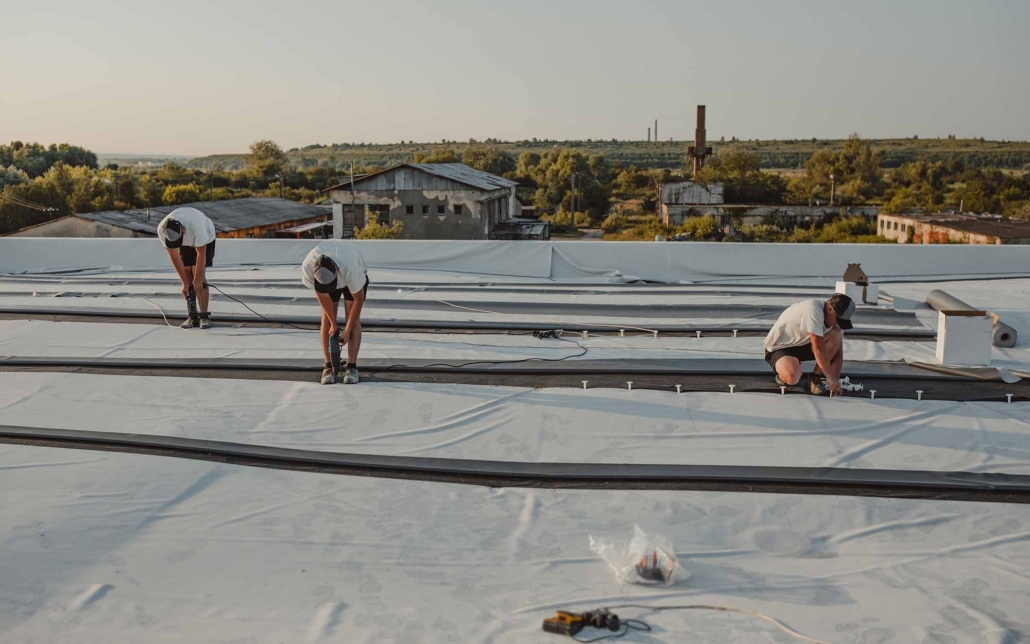 three people working on commercial roof maintenance