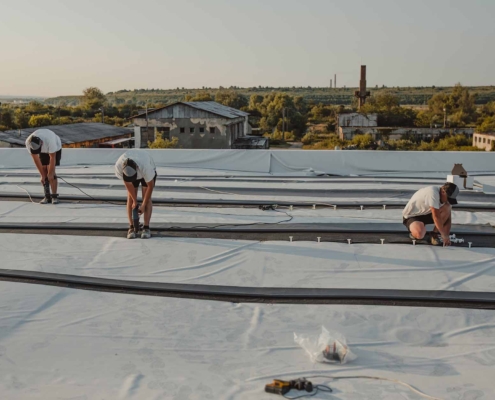 three people working on commercial roof maintenance
