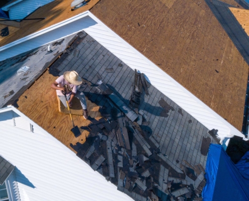 Image of a worker replacing residential roof shingles.